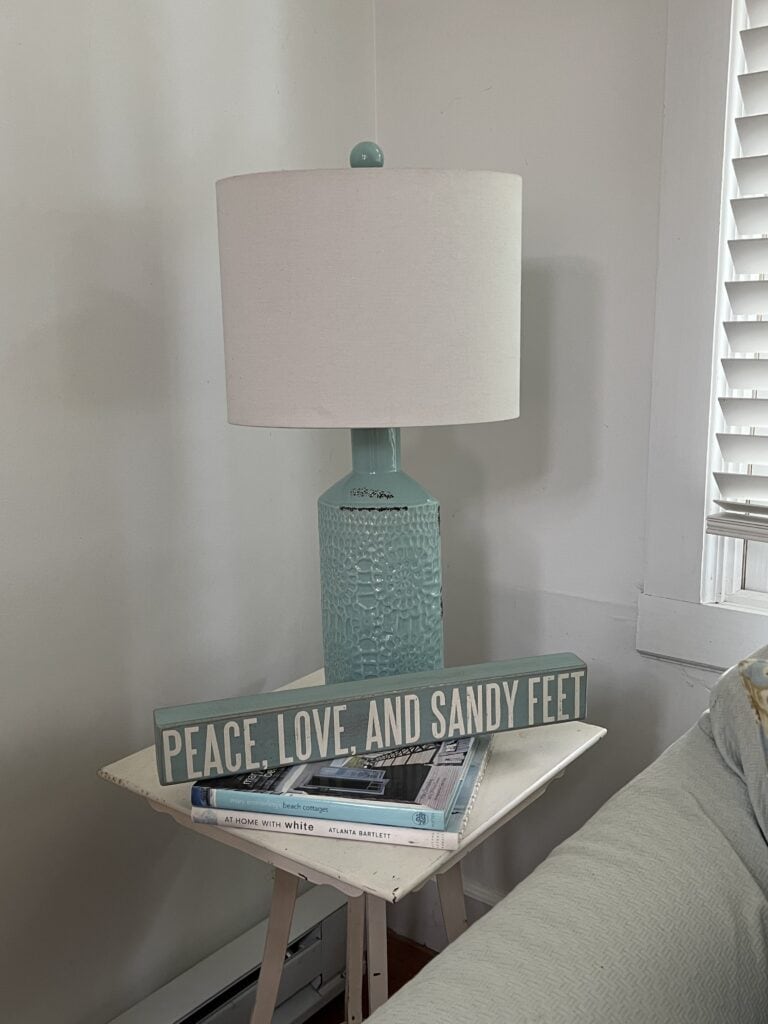 side table with a sign reading "Peace, Love and Sandy Feet"