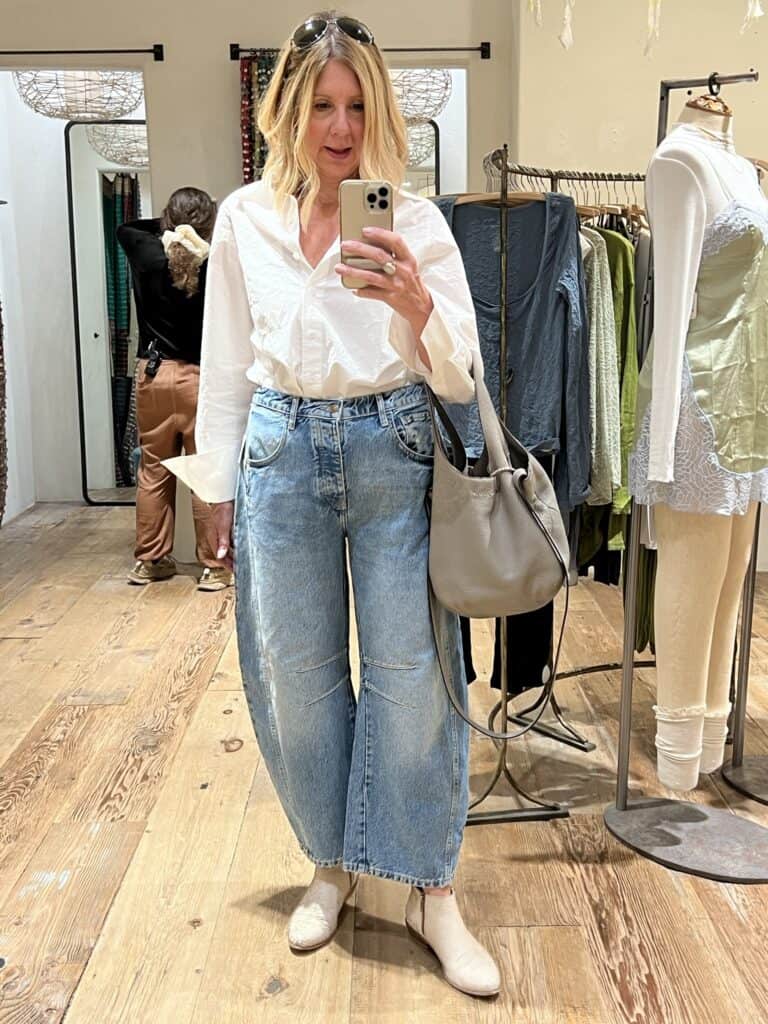 Woman in a white shirt and Free People barrel jeans. 