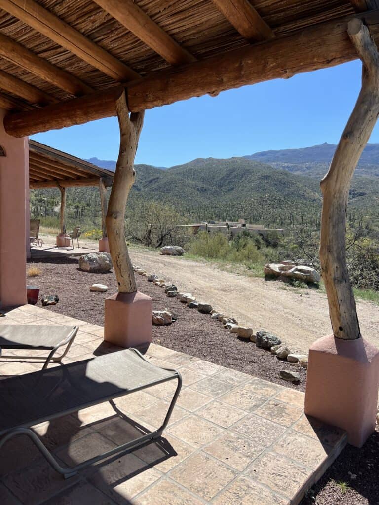 View of the mountains from a porch with lounge chairs. 