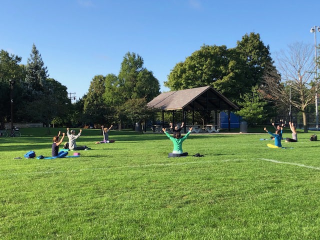 Multiple people doing yoga in a park.