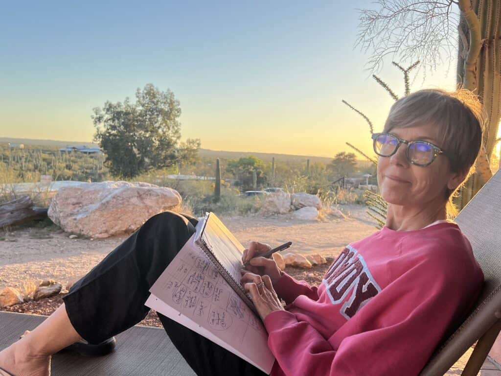 Woman sitting on a porch mapping out the weeks activities for the spring break with teens,  with the sun setting in the background.