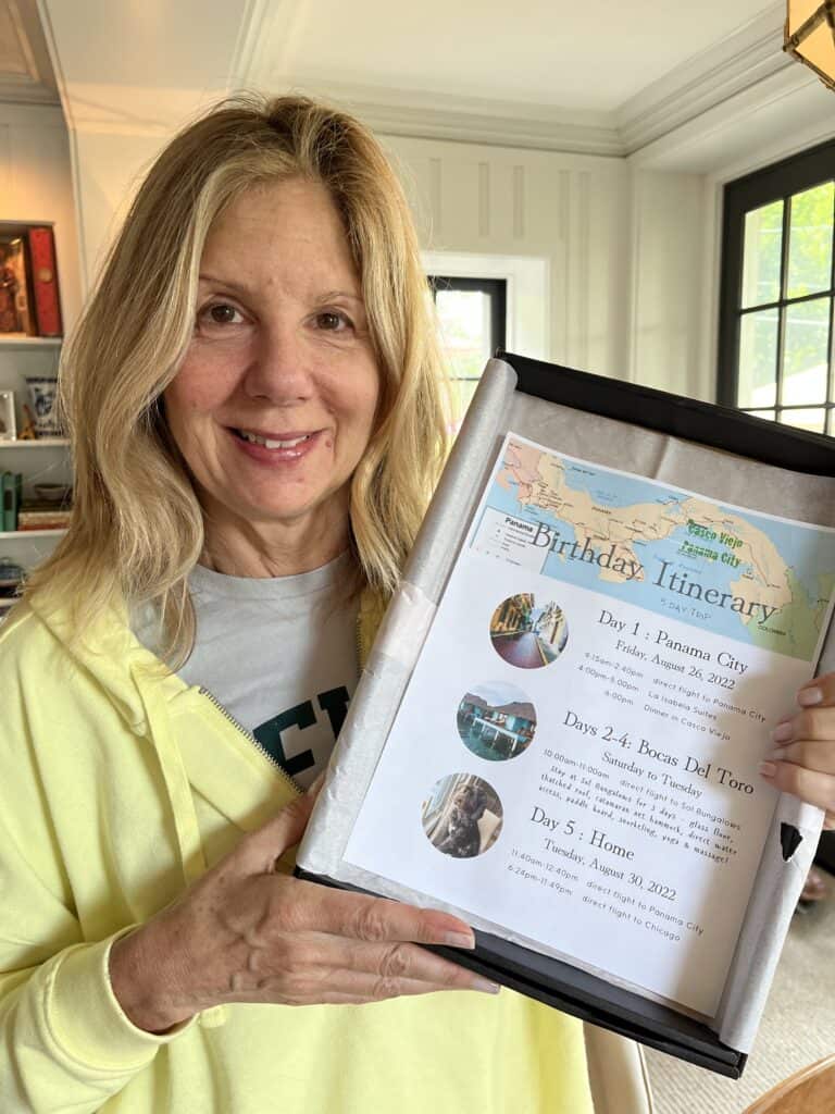 Woman holding a birthday gift of a trip itinerary. 