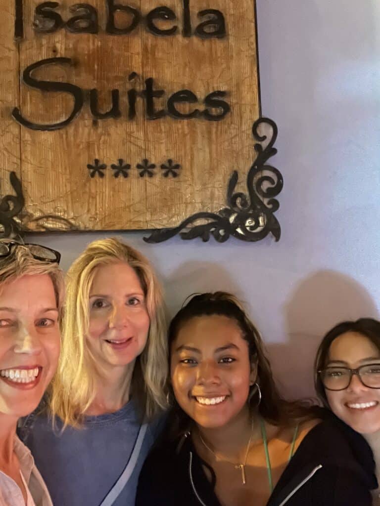 Photo of four people standing in front of a sign for La Isabela Suites Hotel.