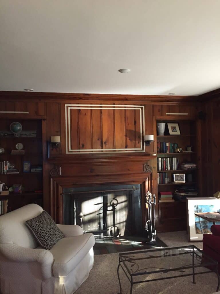 Photo of two different sizes of TVs outlined in masking tape above the fireplace.