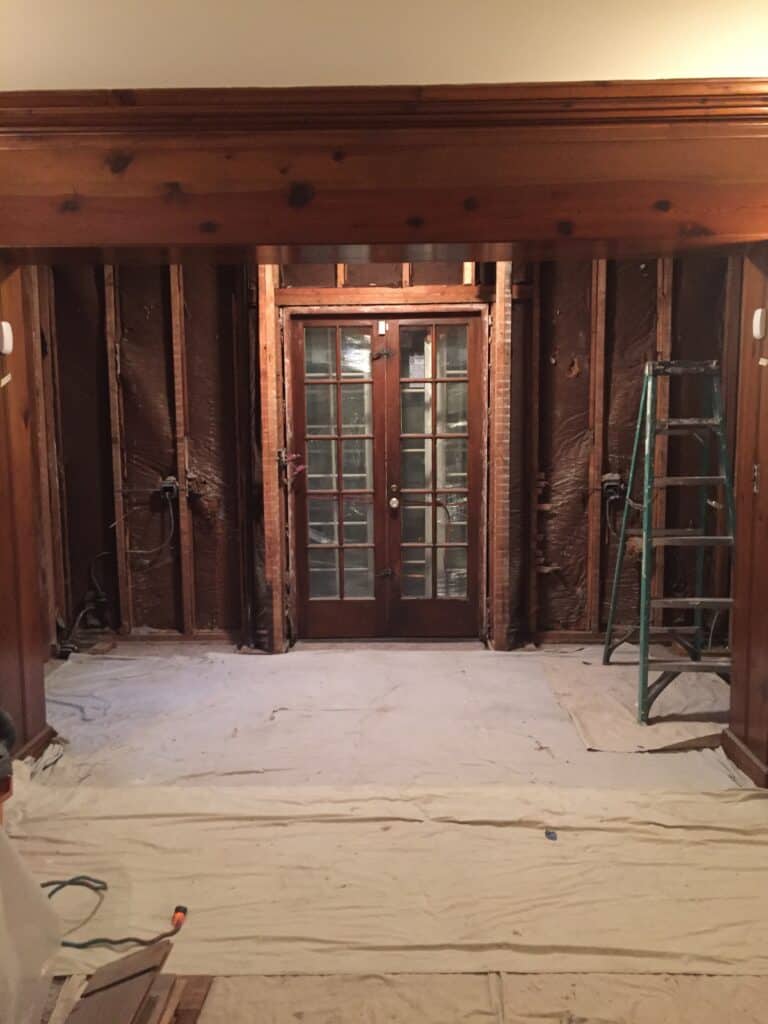 Before, a small set of French doors and a wall under construction with open framing.