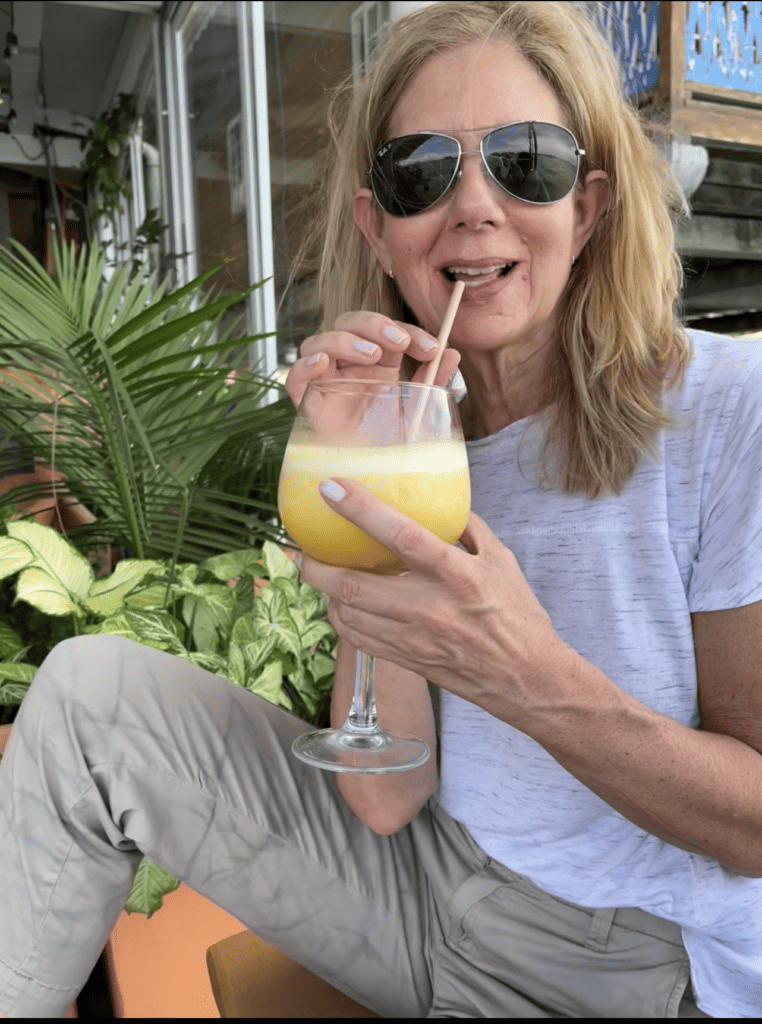Photo of a woman drinking a smoothie, surrounded by lush vegetation.