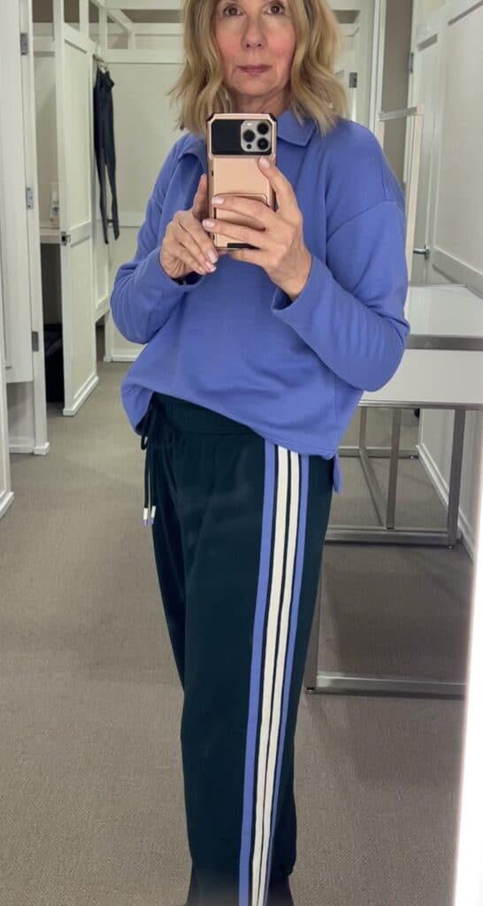 Woman in a dressing room with the green striped pants and a blue sweatshirt that coordinates to the blue color of the stripe.