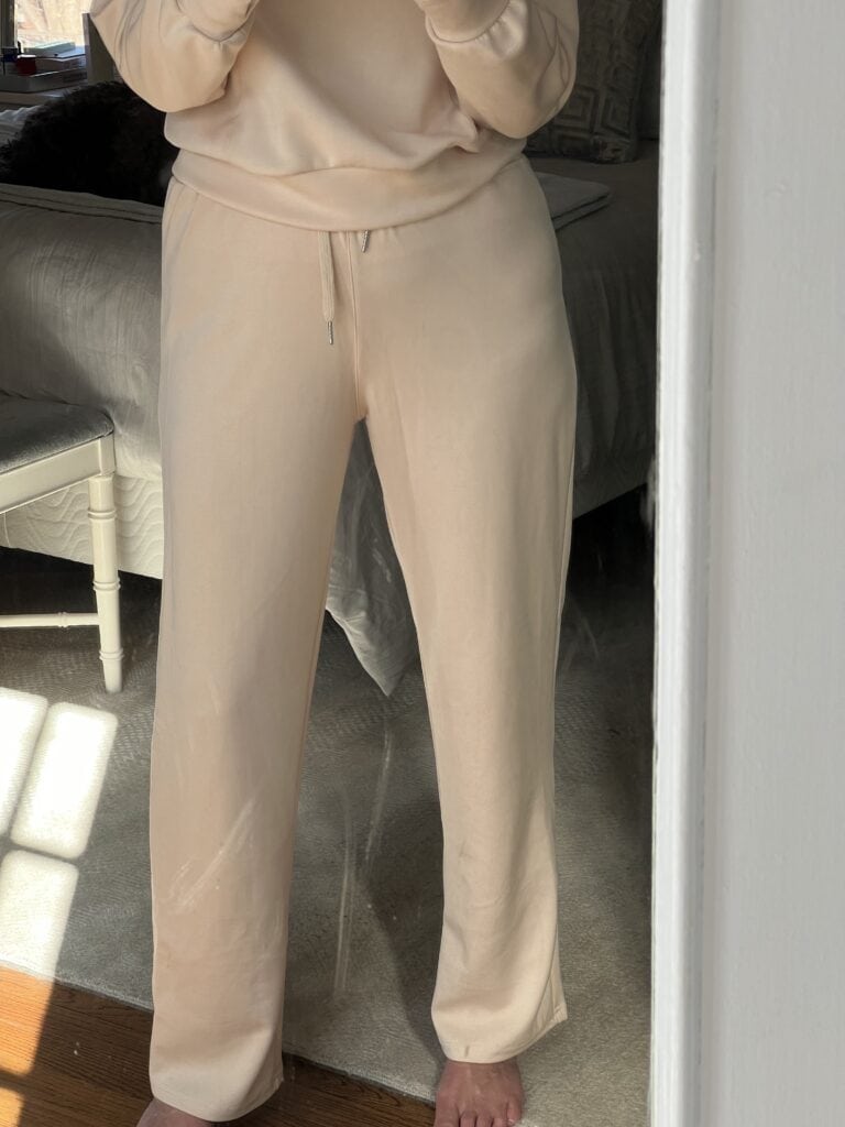 Woman in a cream colored matching set showing close-up of pants.