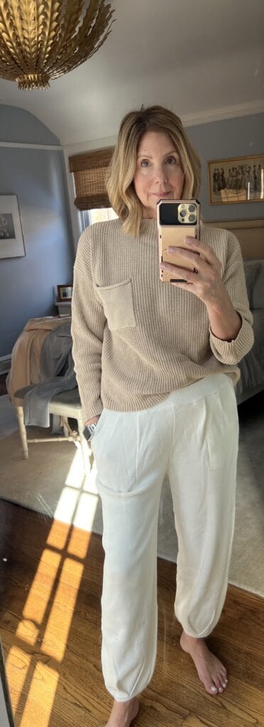 Woman in a 2-piece sweater set with beige top and white pants. 