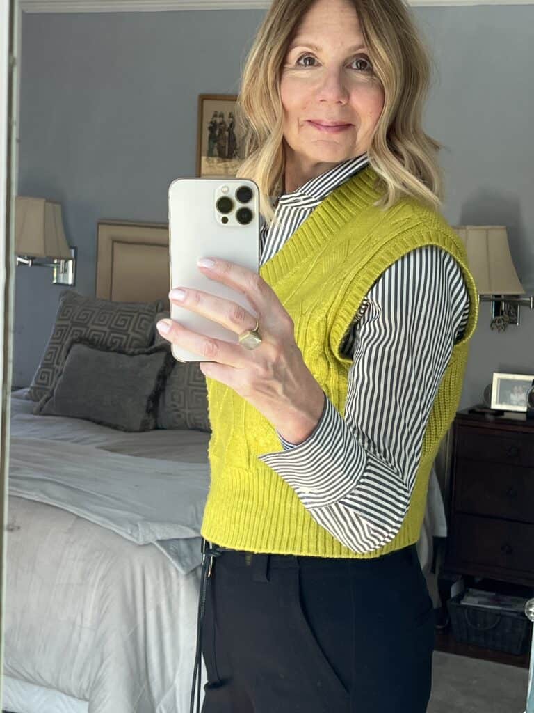 Photo of me in black slacks with a striped button down shirt and yellow sweater vest.  As I demonstrate how I adapted my style to my body type.