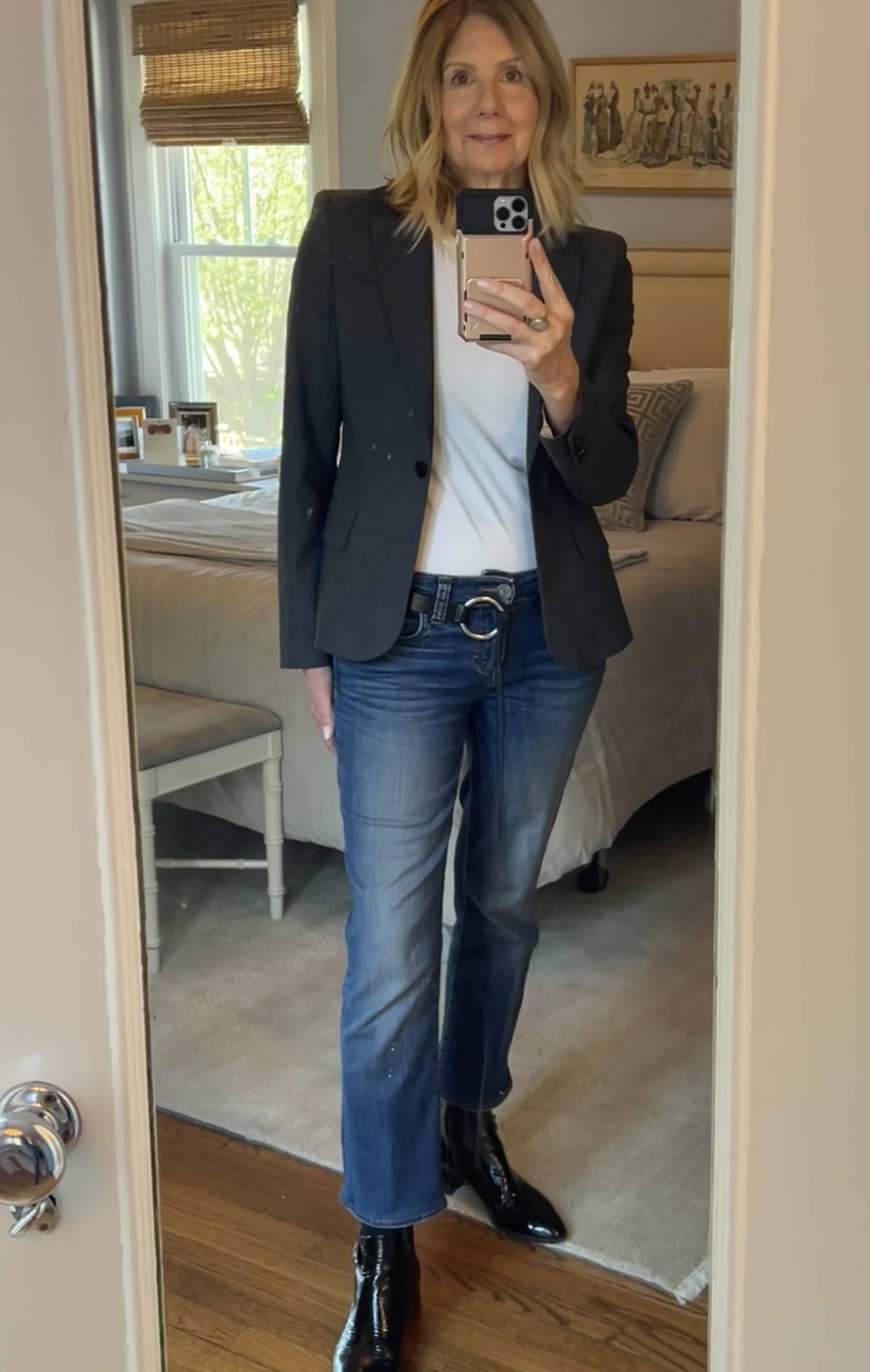 Photo of a woman wearing a grey blazer, white t-shirt and jeans.