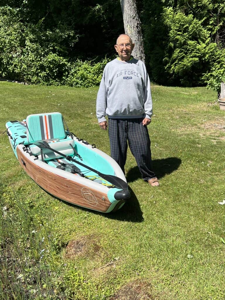 Man standing by the newest addition of water toys at the lake, a BOTE kayak.