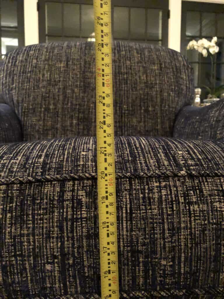 Close up of a measuring tape against the chair with a swivel base, measuring nearly 22 inches. 