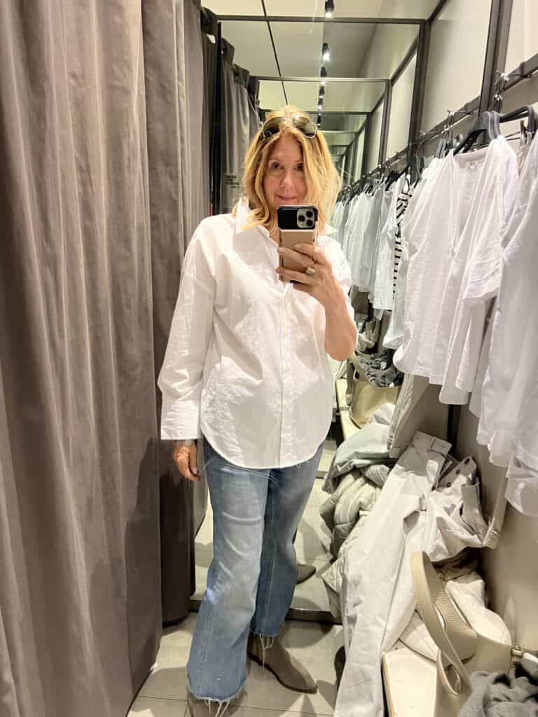 Photo of a woman in a white button down shirt in a dressing room. 