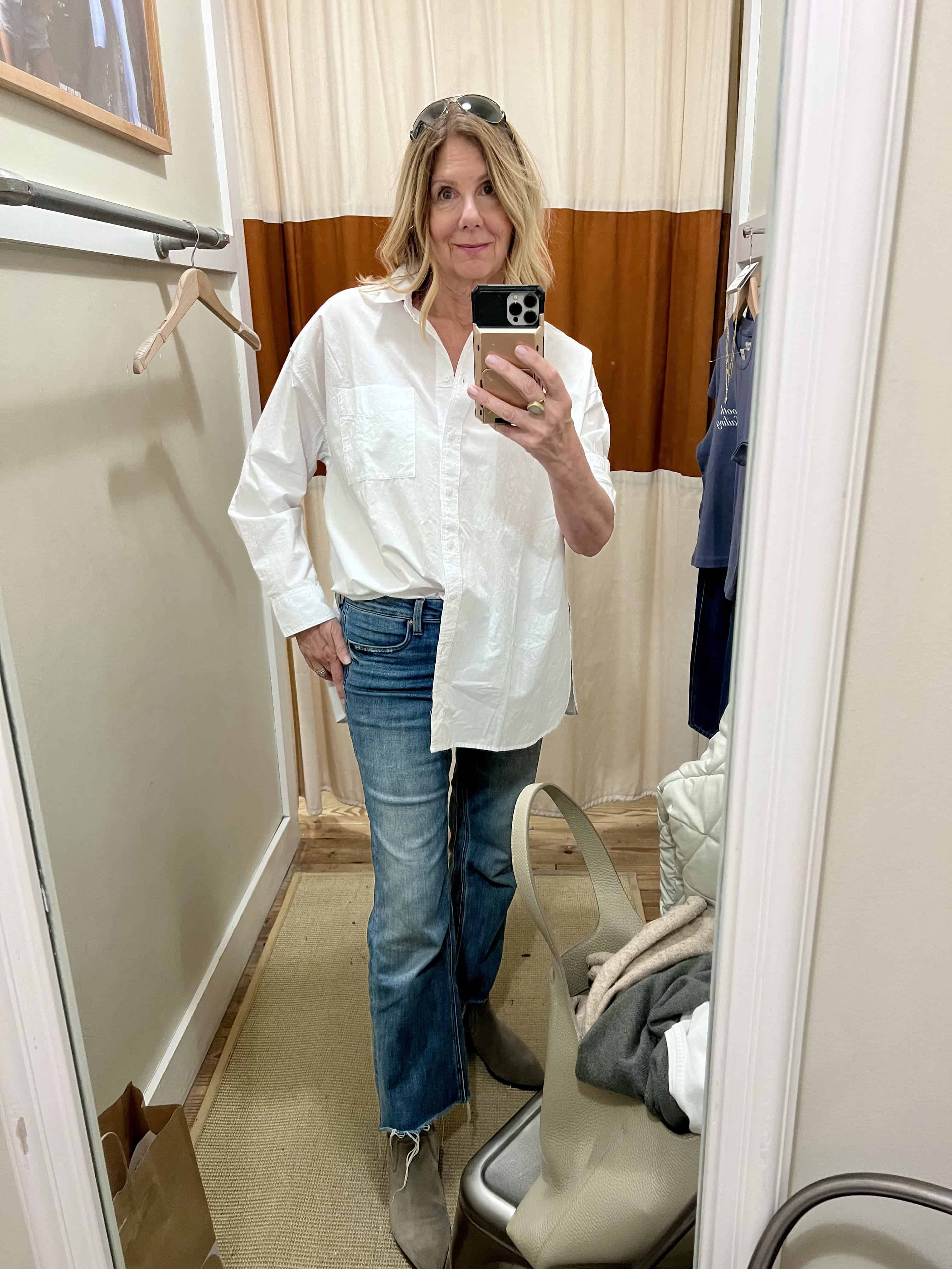 Woman in a dressing room with a white shirt half tucked in. 