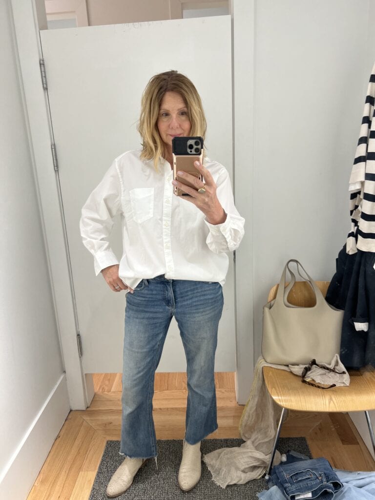 Woman in a Gap dressing room trying on a shirt that is tucked in. 