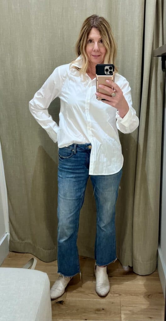 Woman in a Banana Republic dressing room trying on a half-tucked white button-down shirt. 