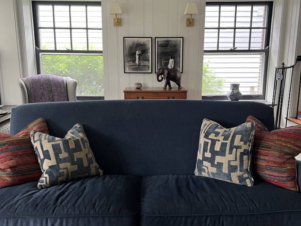 Sofa with the colorful pillows, beyond are photos from Africa and a large carved Elephant, the essence of Nancy Meyers meets Jane Goodall style.