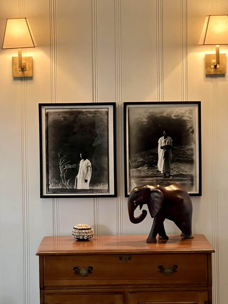 Close up of photographs of a woman in Africa, with a carved elephant in the foreground.