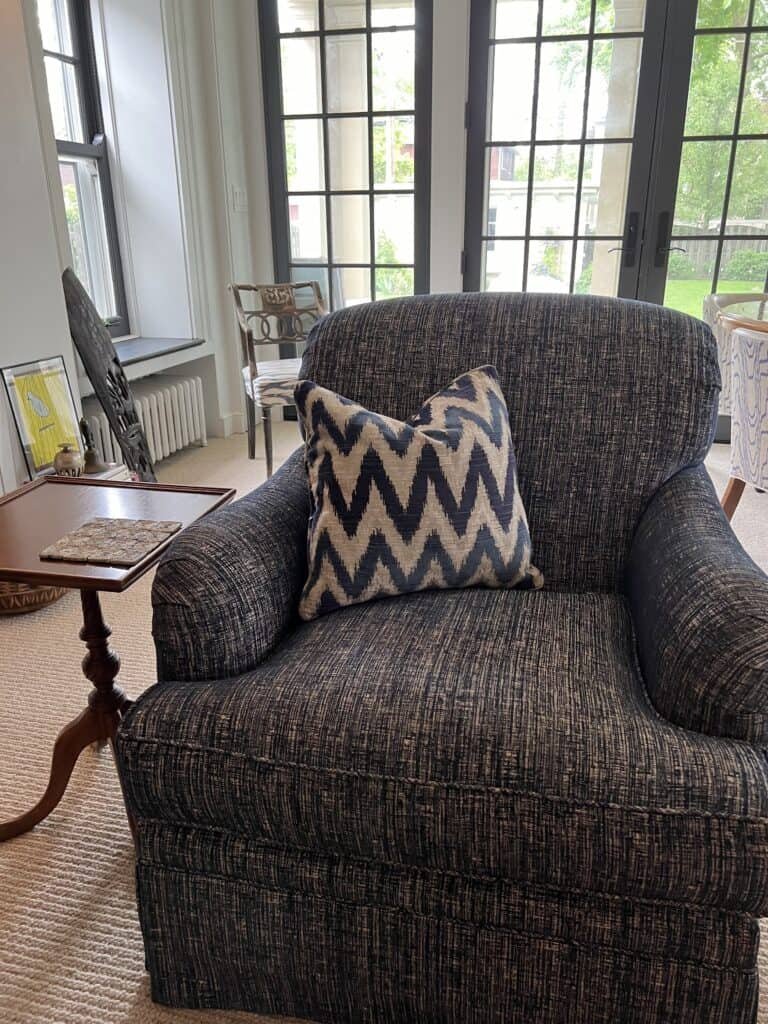 Blue upholstered club chair with a pillow in the fabric of the arm chair. 