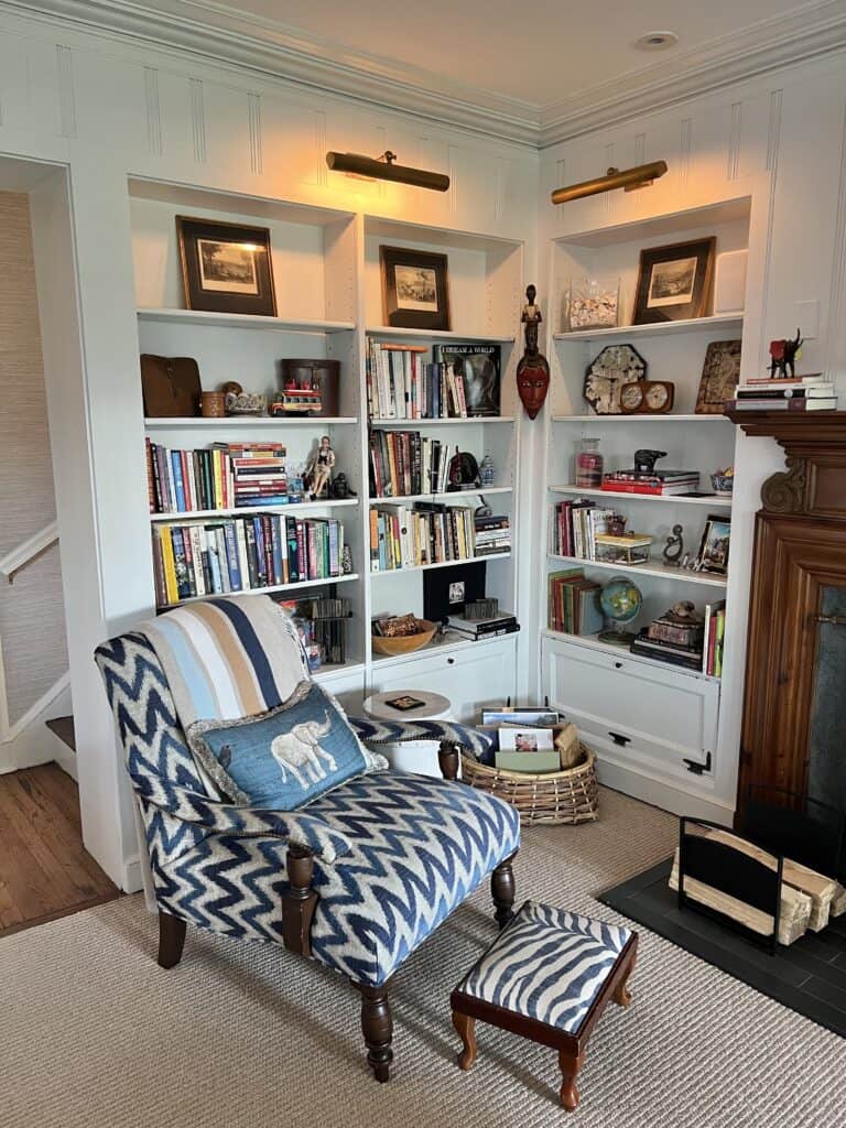 Photo of a corner in the family room with two walls of bookshelves and a chair with elephant pillow, visualizing the Nancy Meyers meets Jane Goodall Style