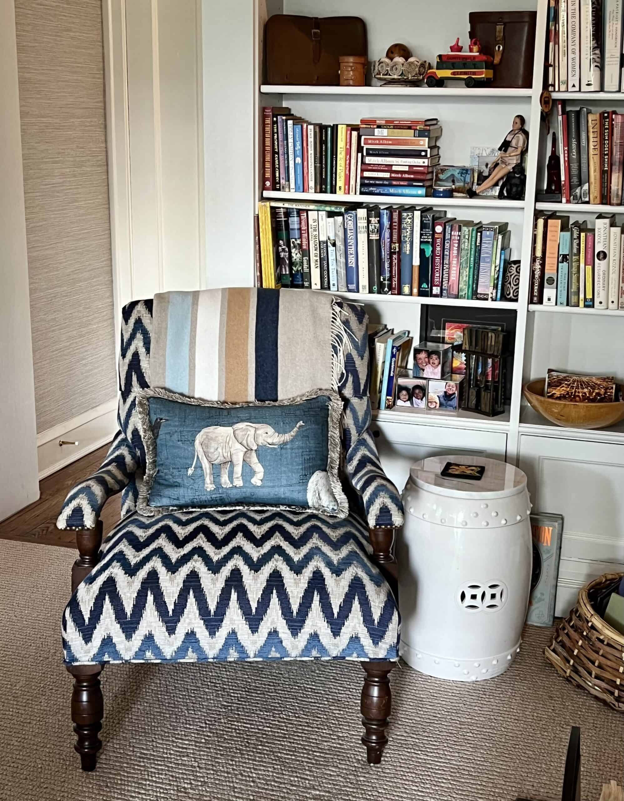 Close up of arm chair upholstered in zig zag graphic fabric with a striped blanket and elephant pillow. 