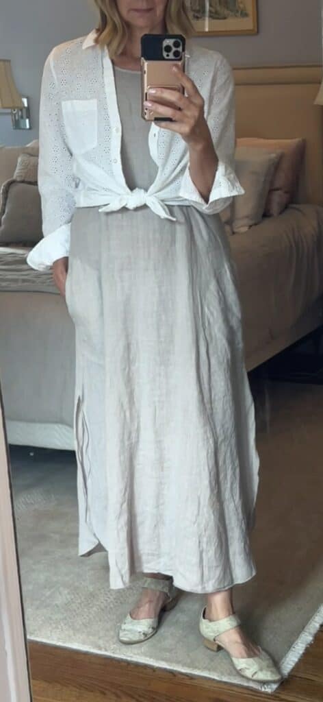 Woman with a white eyelet shirt tied at the waist over a sundress.