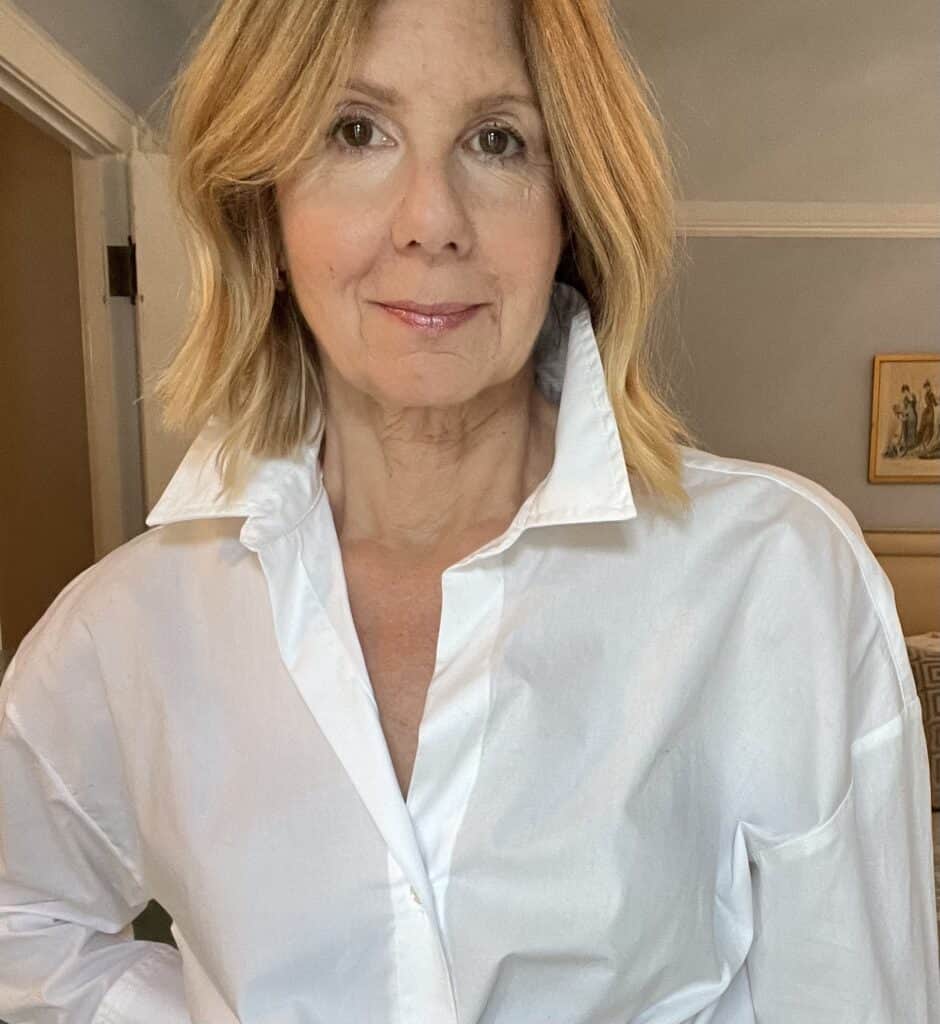 Woman styling a white button-down shirt with the collar up. 