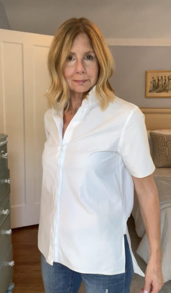 Woman in a short-sleeve white button-down shirt left untucked. 