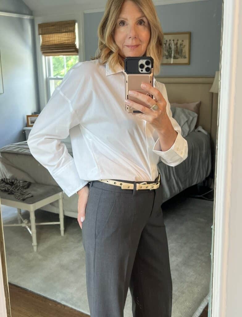 Woman with a white button-down shirt tucked into grey slacks.