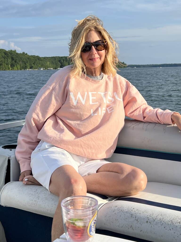 Woman in a peach Comfort Colors sweatshirt with WETSU Life written on it. 