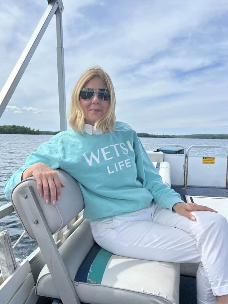 Woman sitting on a boat in a teal Comfort Colors WETSU Life sweatshirt