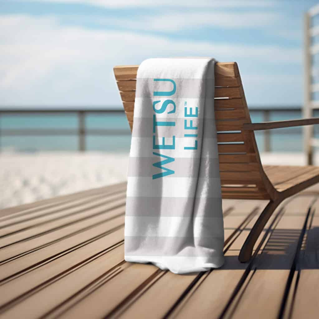 The WETSU Life cabana stripe beach towel draped over a chair