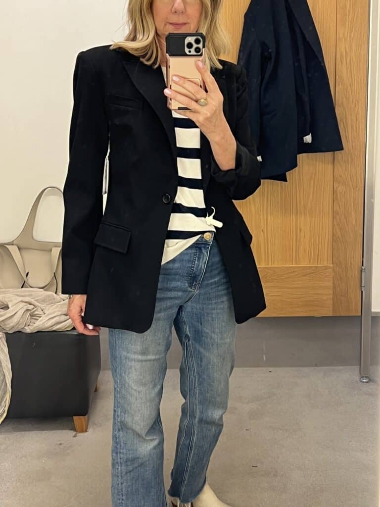 Woman trying on a black blazer in her quest to do a fall wardrobe refresh. 