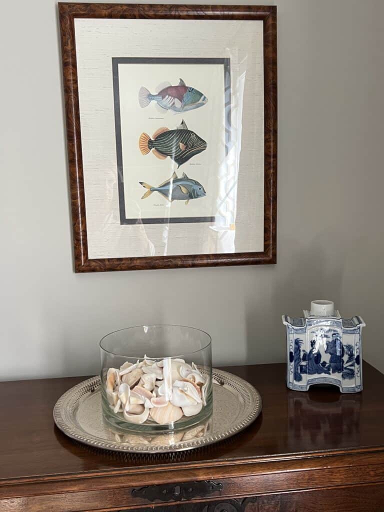 Vignette of fish print, bowl of shells and Chinese pottery.