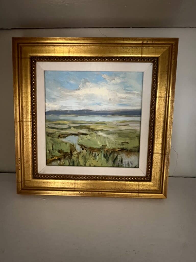 Oil painting in gold frame with light blue water and blue sky, continuing the theme of water creating a sense of interior design flow. 