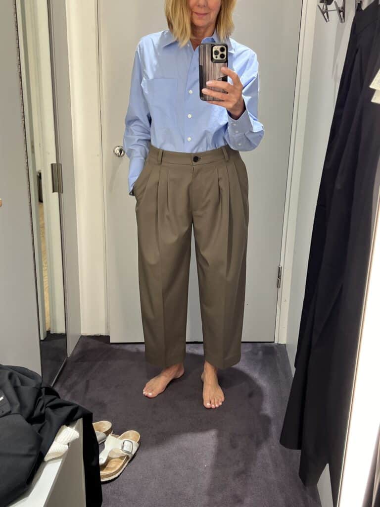 Woman in the dressing room at COS, trying on a pair of wool-blend, barrel shaped dress pants to add to her fall wardrobe.  