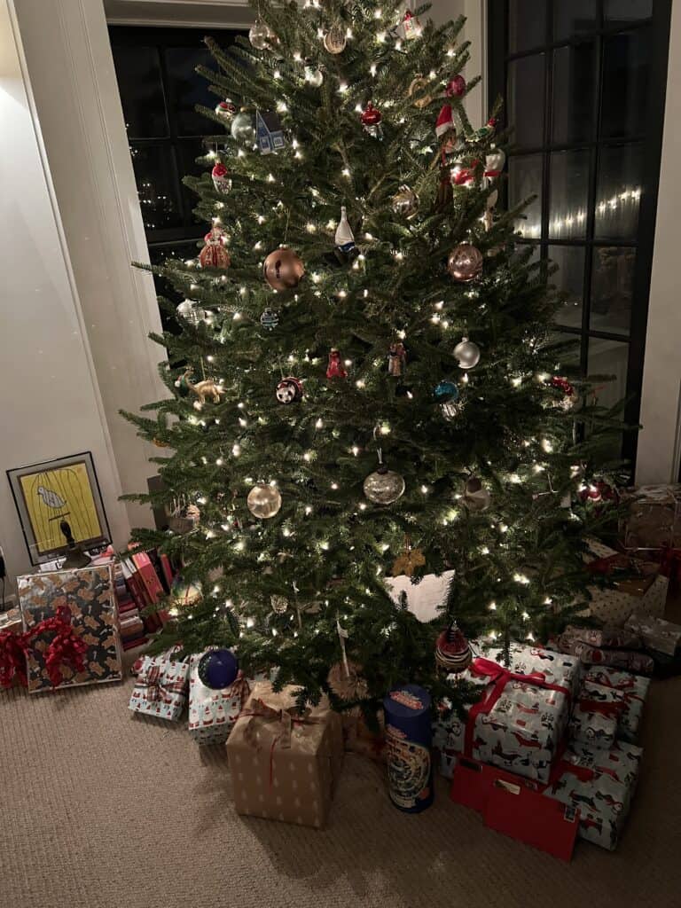 Photo of a Christmas tree with white lights and gifts below the tree. 