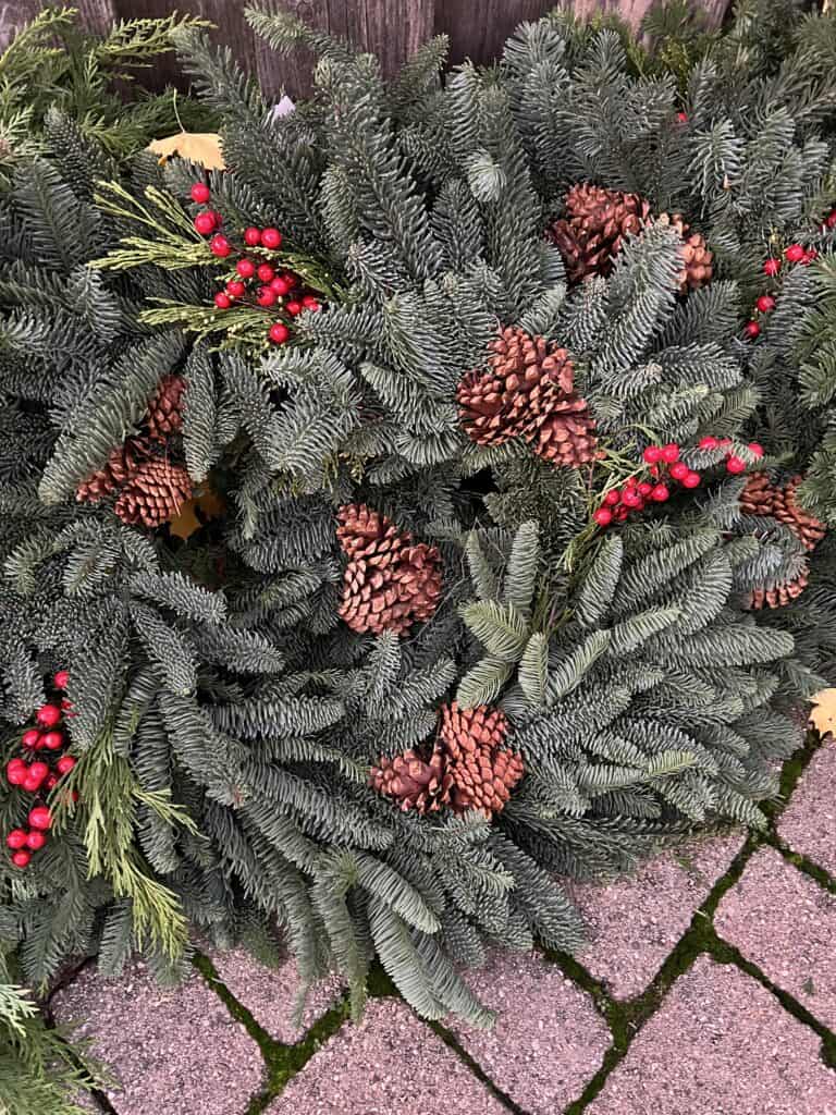 Close up of a fresh wreath of Noble Fir, pine cones, cedar and red berries.  