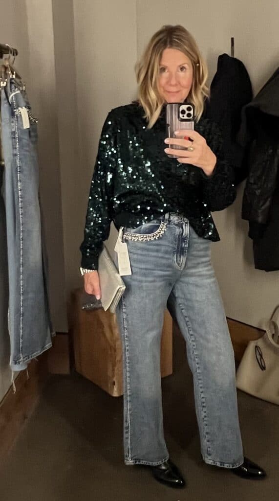 Women trying on a green sequin top and jeweled jeans for a holiday outfit. 