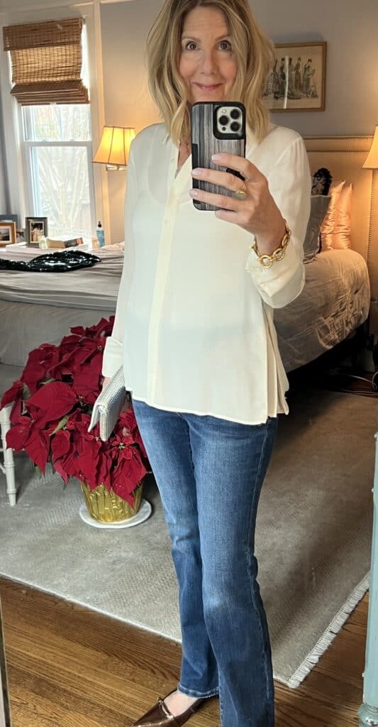 Woman in flare jeans, kitten heel pumps and a cream silk blouse. 