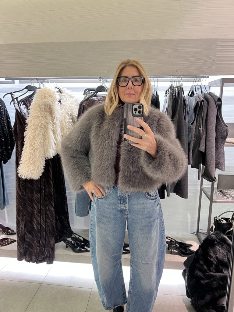 Woman trying on a grey fuzzy Zara faux fur jacket.