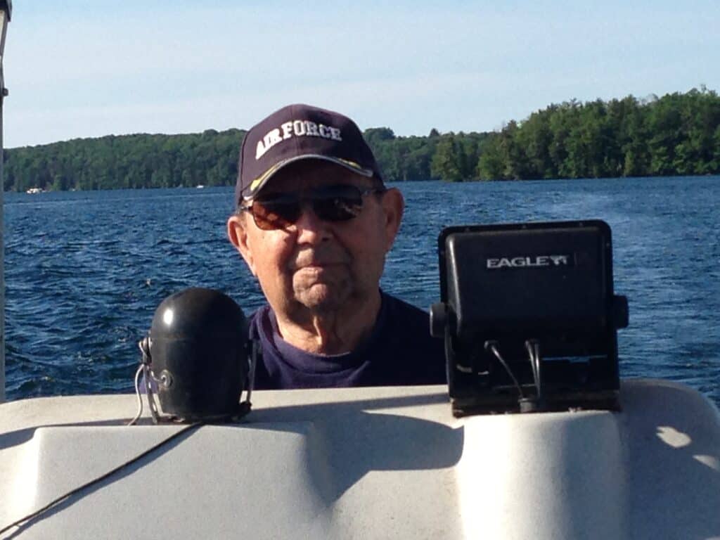 Dad, driving the pontoon boat with his Air Force hat on. 
