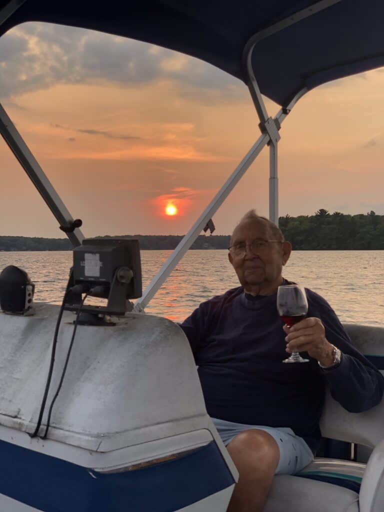 Photo of my Dad driving the pontoon boat at sunset, with a glass of wine in hand. 